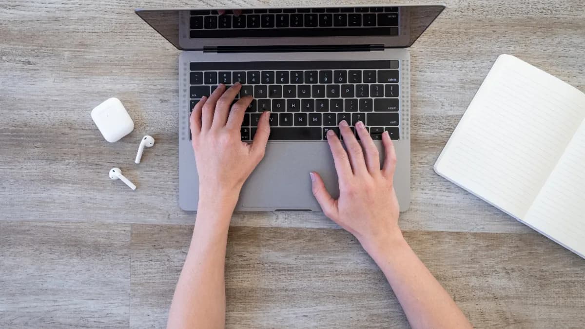 ノートPCのキーボードに手を置いて入力しているイメージ写真